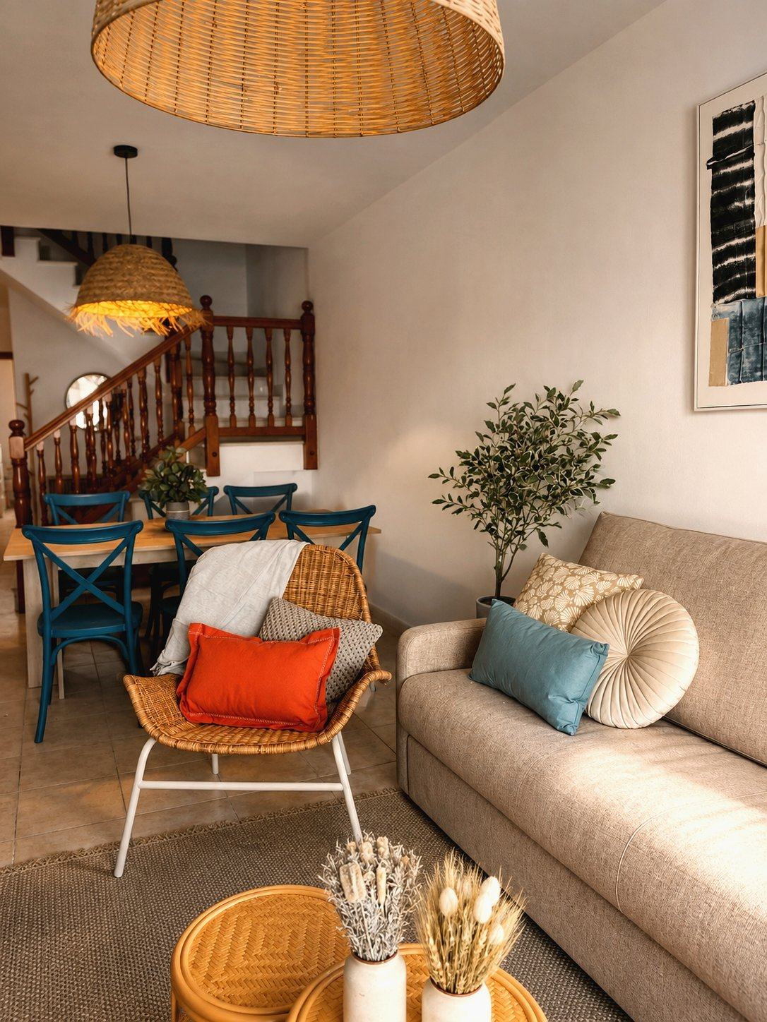 Salón de Casa Timanfaya, con sillón de ratán, sofá y cojines en tonos tierra y azul